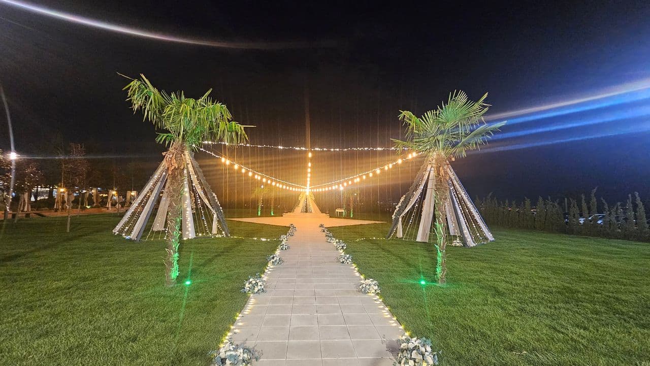 Palmiyeler arasında ışık zincirleriyle süslü nikah alanı, gece