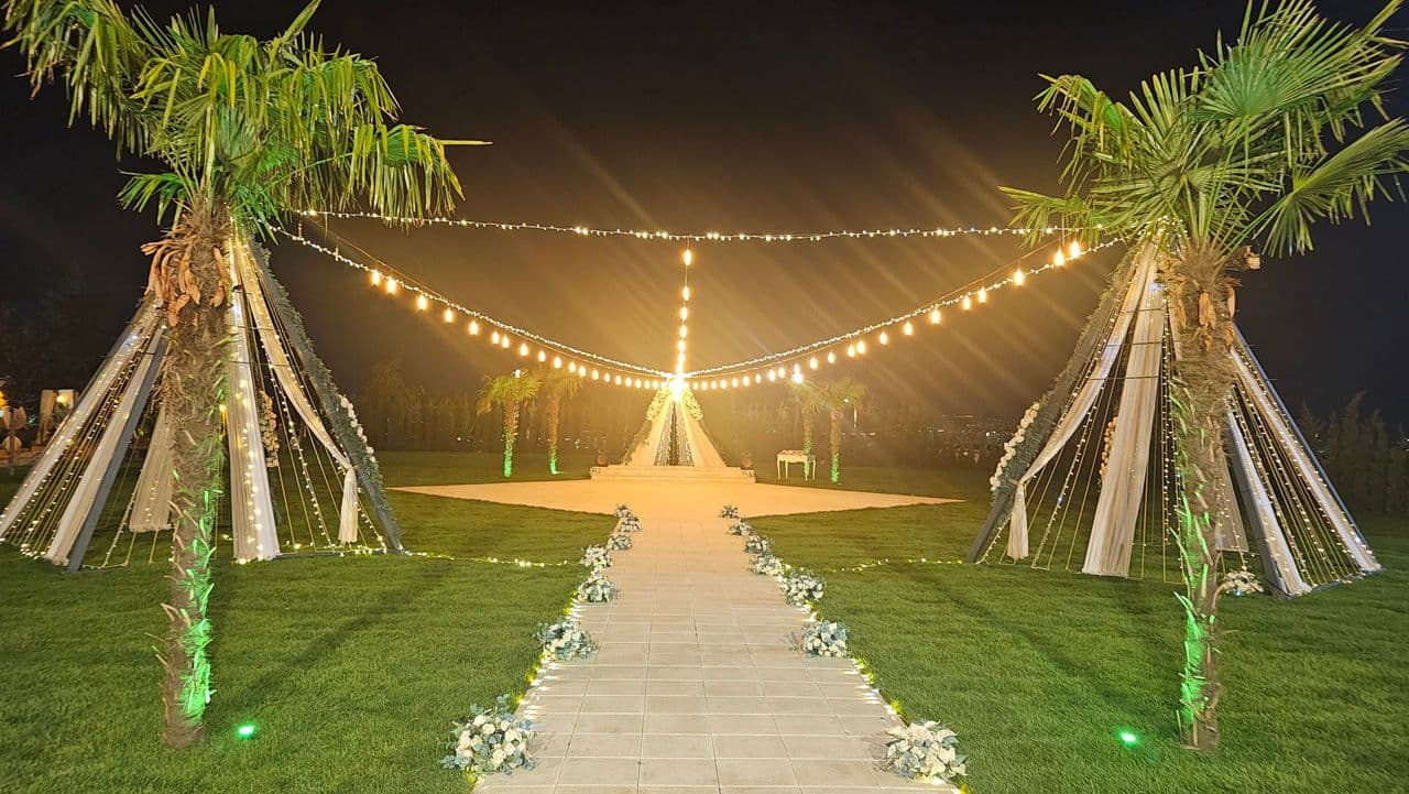 Gece ışıklarıyla aydınlanan nikah alanı ve çiçekli nikah yolu