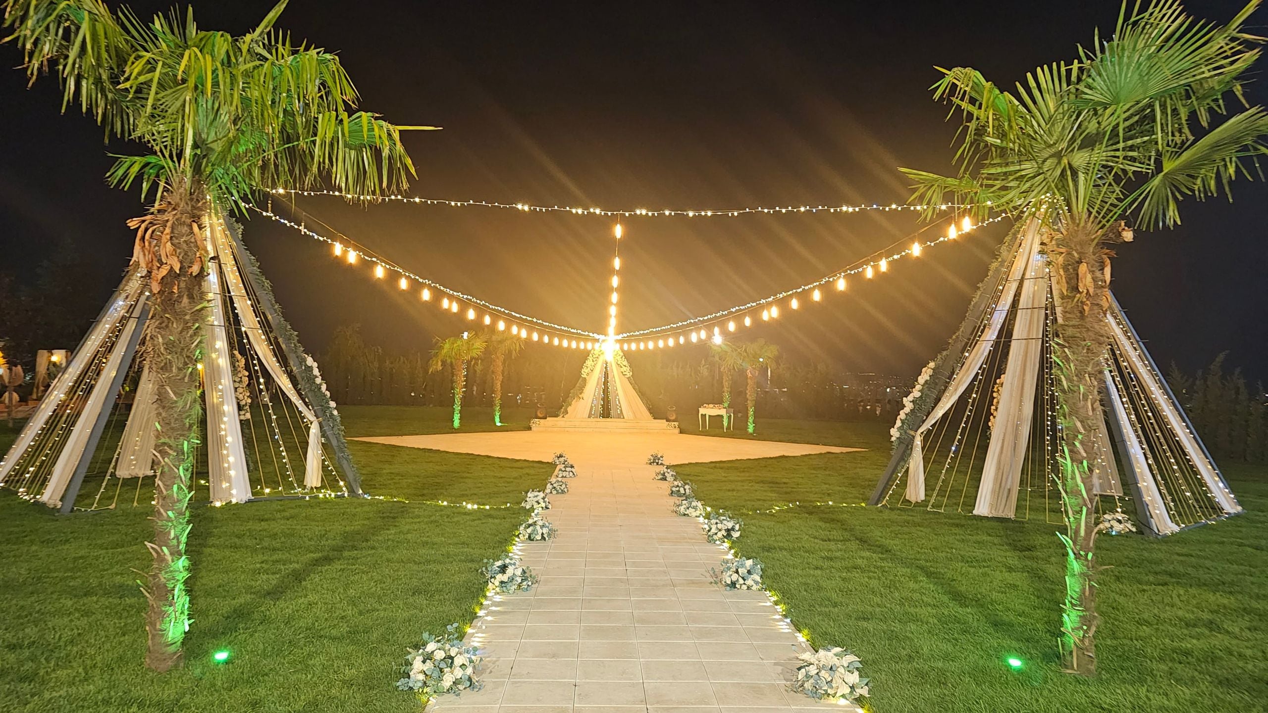 Gece ışıklarıyla aydınlanan nikah alanı ve çiçekli nikah yolu