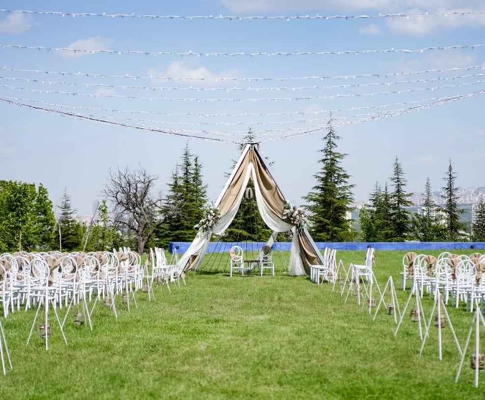 Gündüz vakti ışık zincirleri ve beyaz sandalyelerle nikah alanı